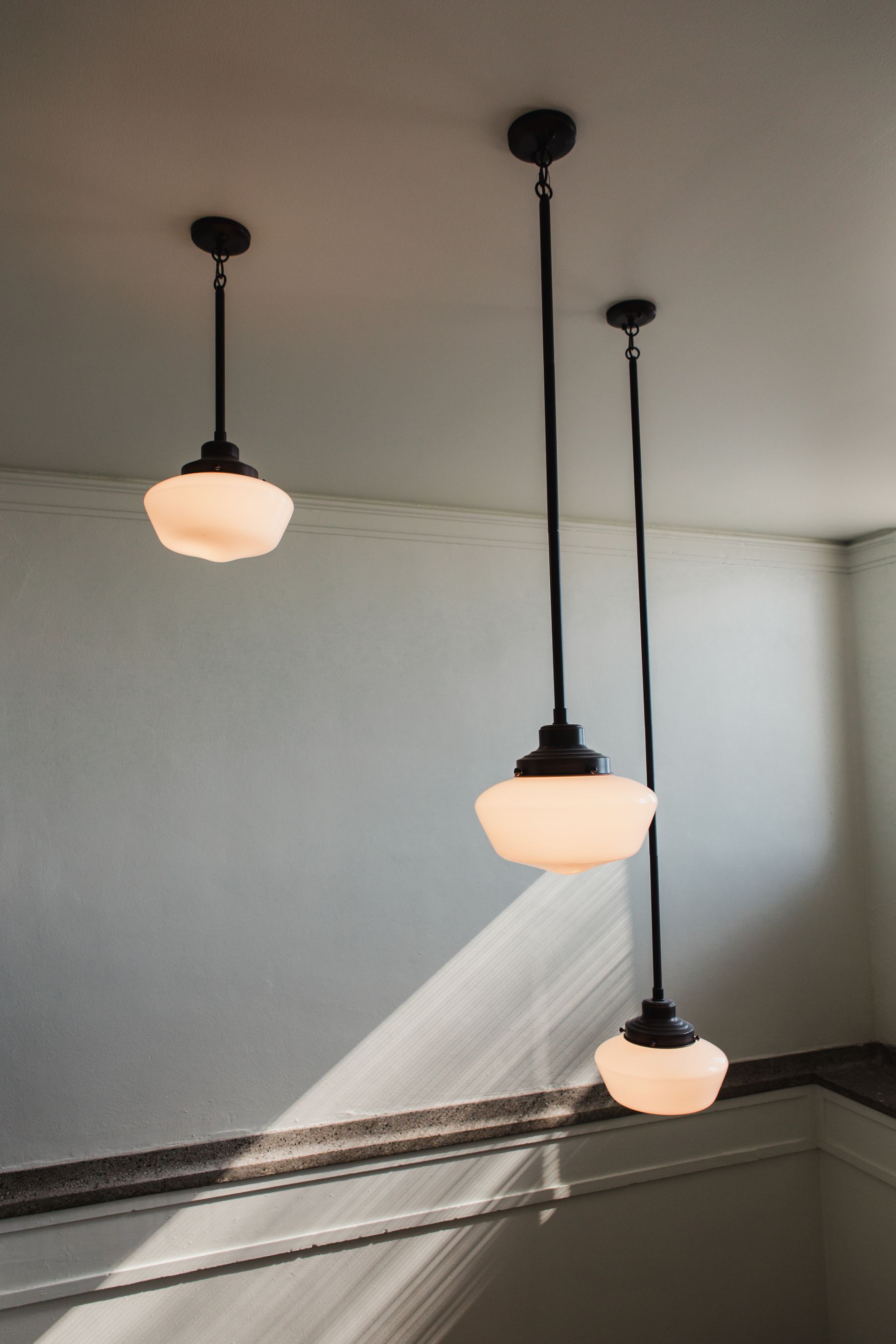 Three pendant lights with frosted glass shades hanging from a white ceiling, above a staircase at Zenith, offers apartments for rent in Duluth, MN.