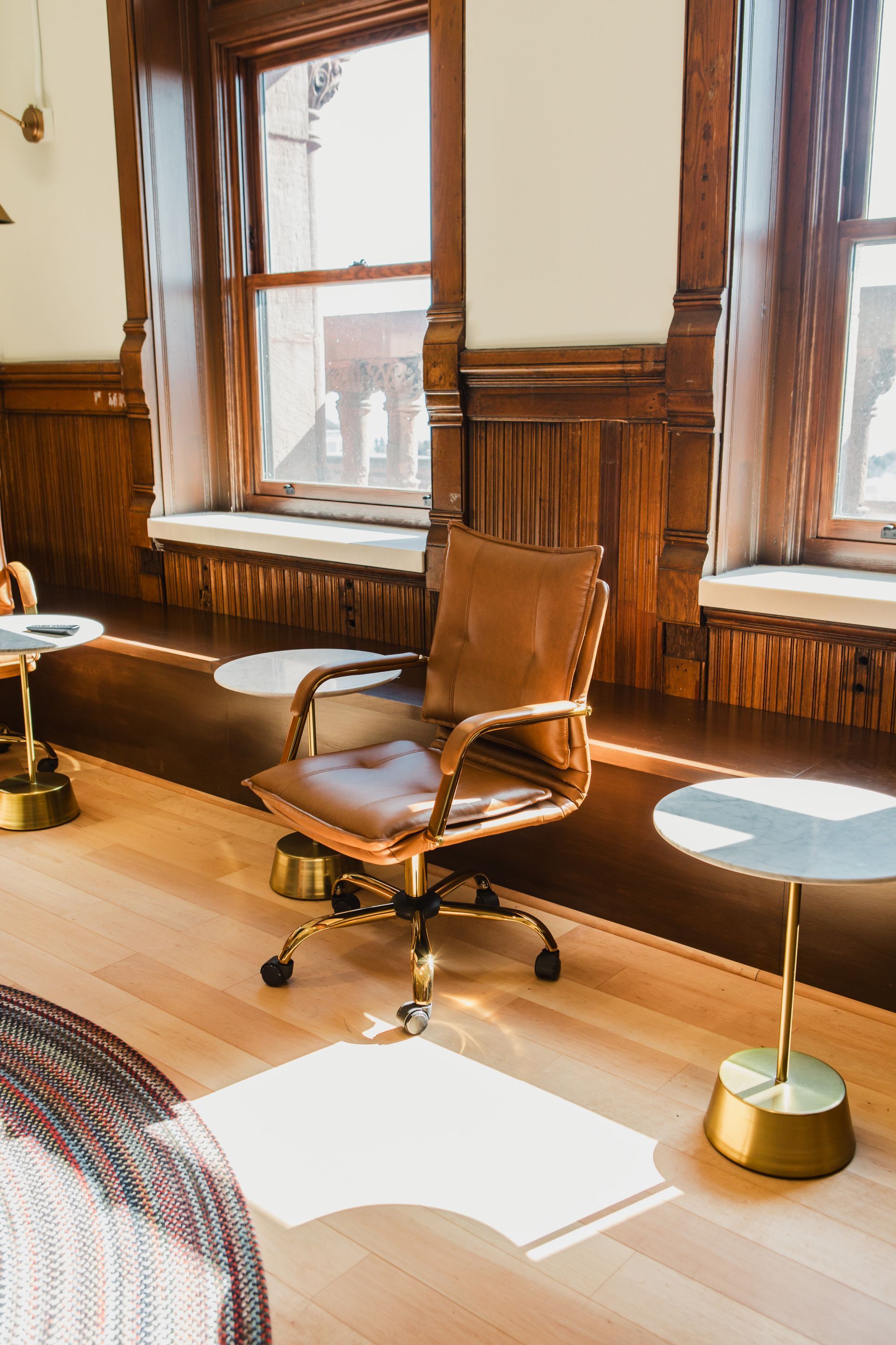 Leather office chair in a room with hardwood floors, natural light, and ornate wood paneling.