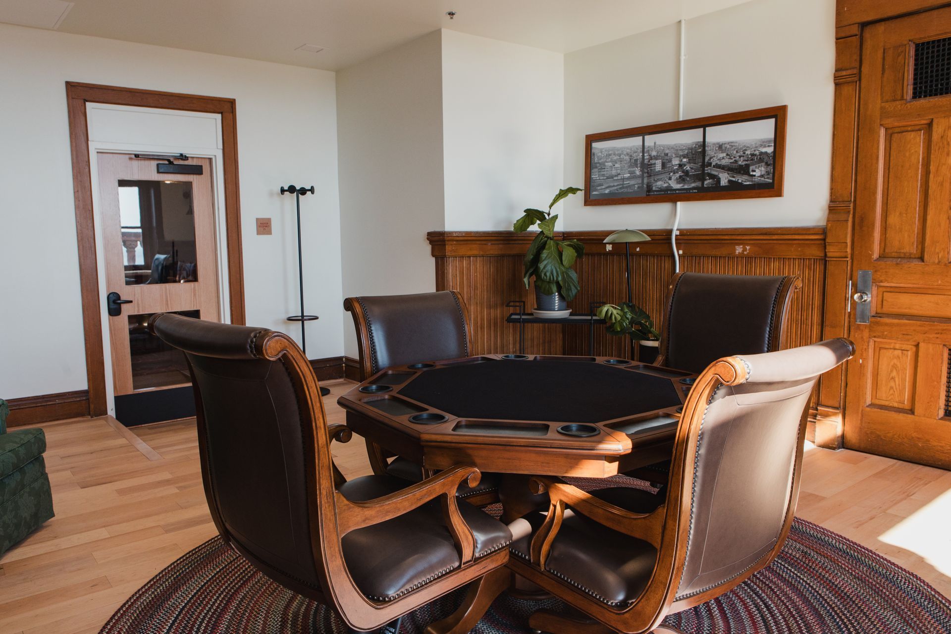 Poker table with four leather chairs in a wood-paneled room.