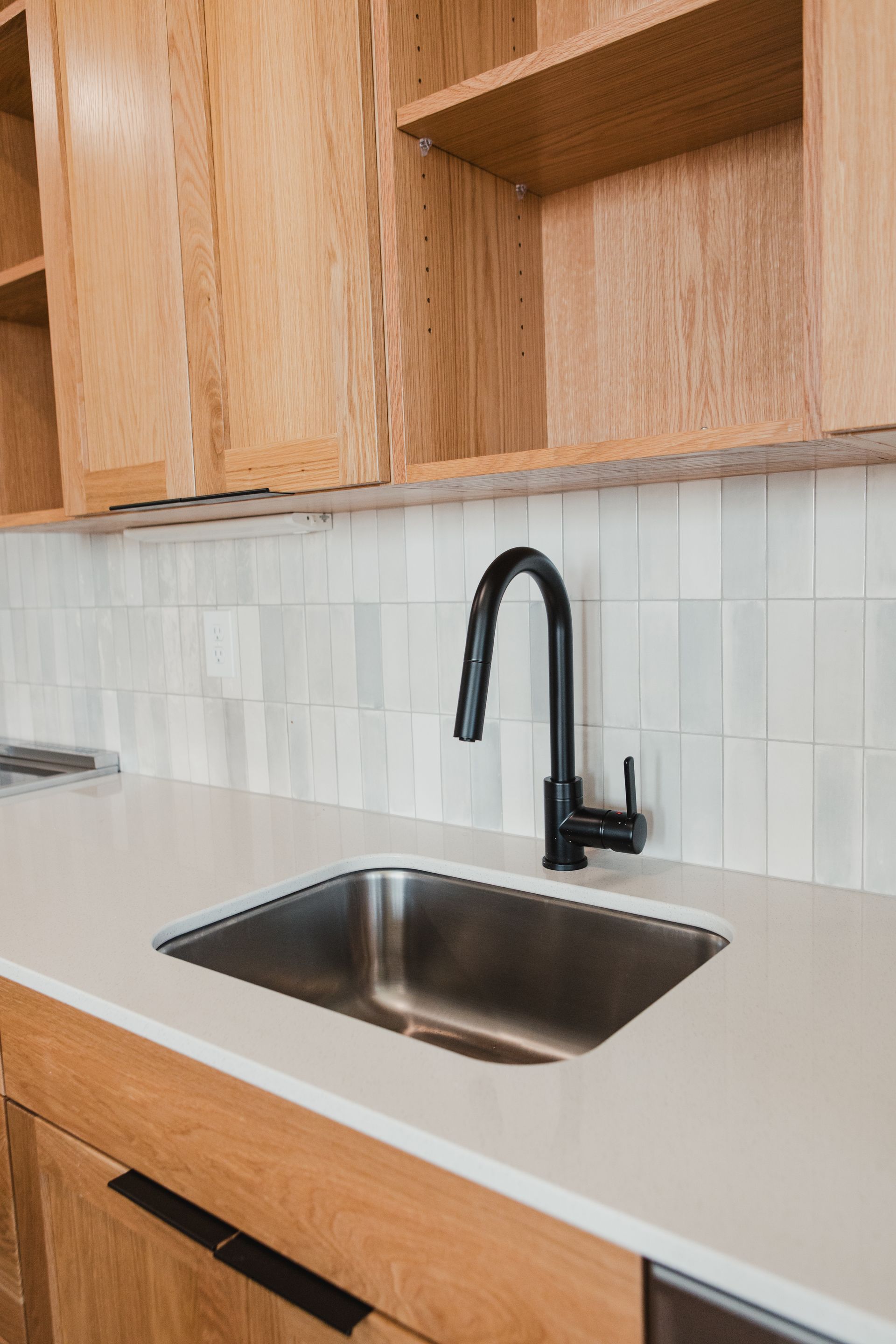 Modern kitchen with light wood cabinets, stainless steel appliances, and white countertop.