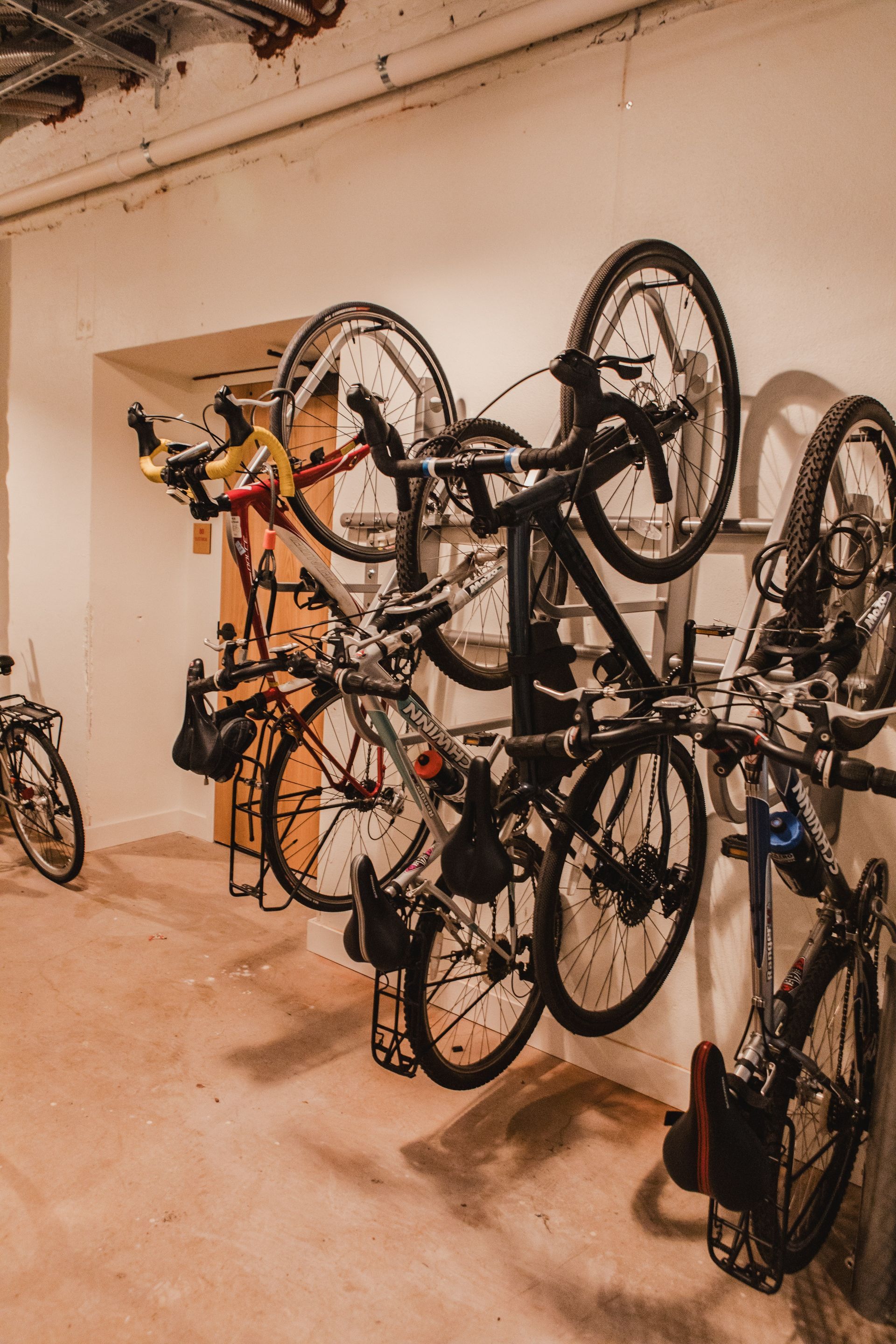 Bikes stored vertically on wall-mounted racks in a concrete-walled room.