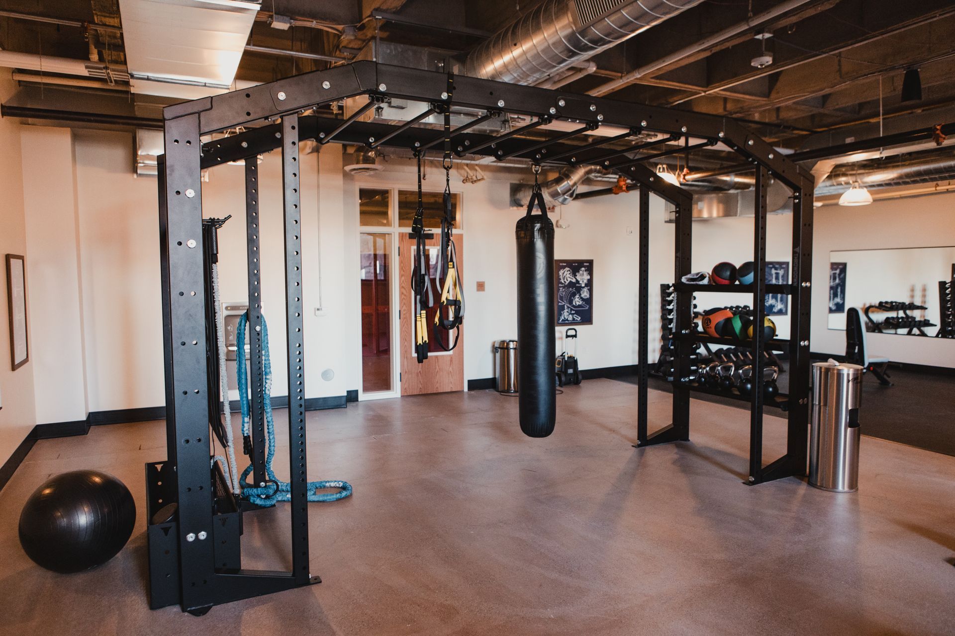 Gym interior with workout equipment, including a punching bag, weights, and a climbing structure.