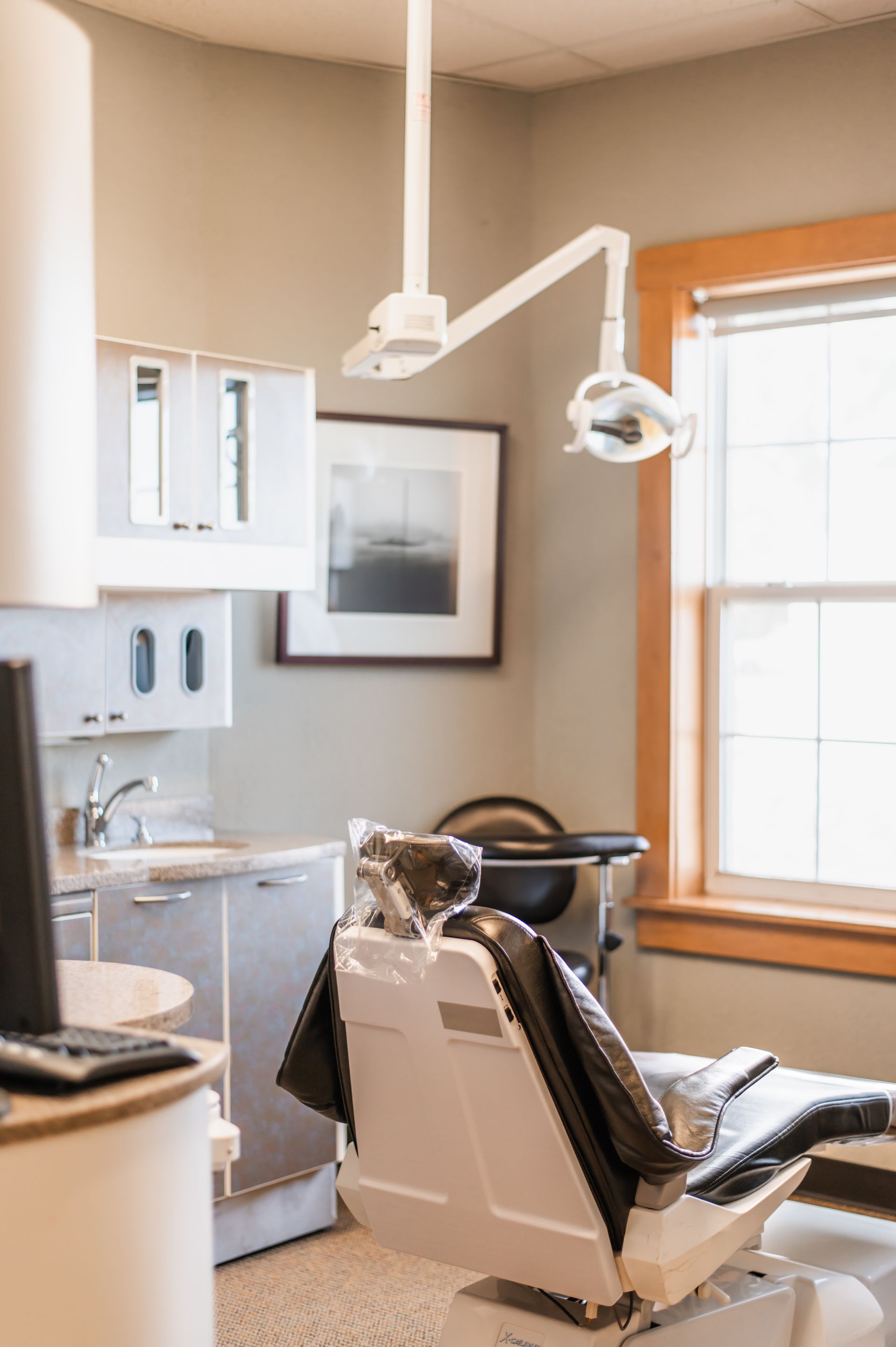 Dental exam room with chair, overhead light, sink, and window with blinds