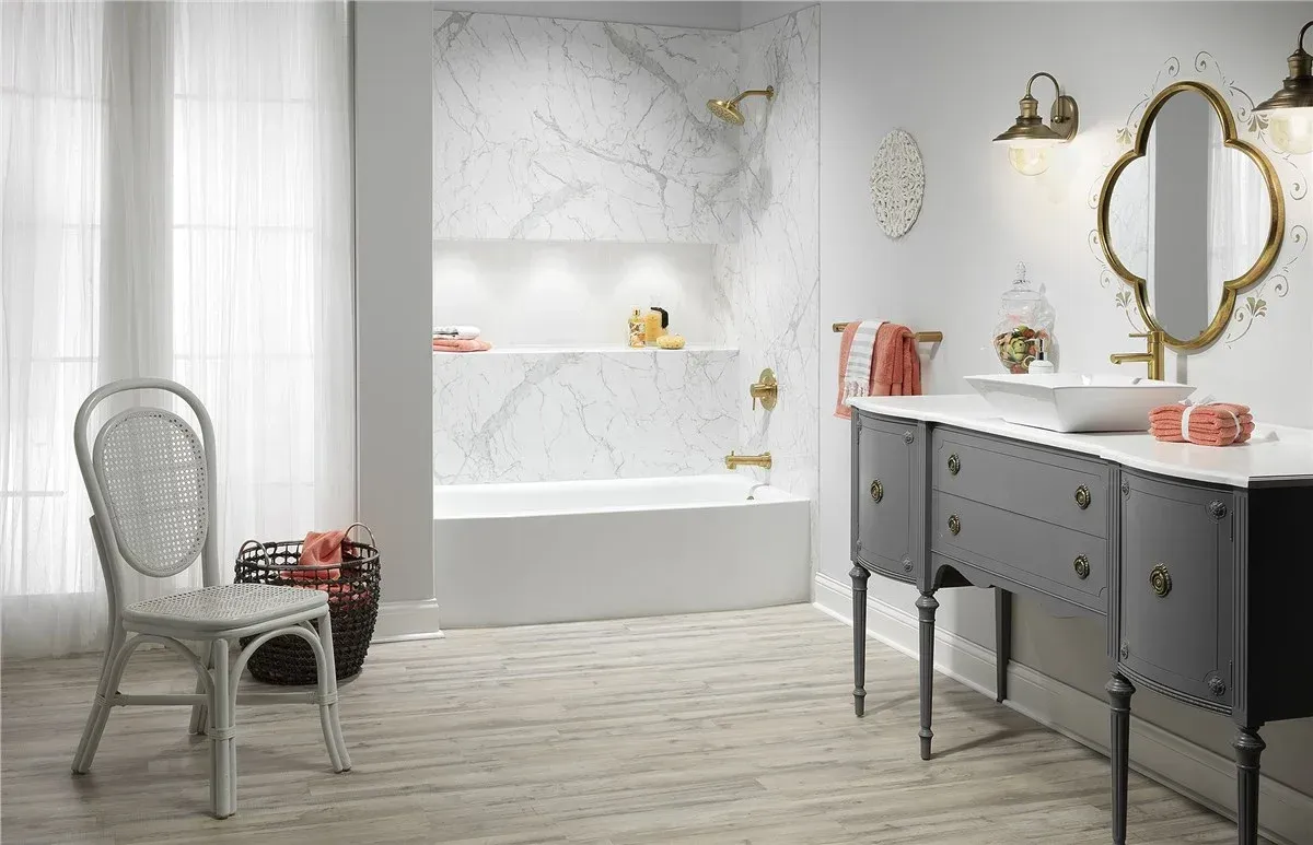 Elegant bathroom with marble walls, freestanding tub, black vanity, and wicker chair beside a window