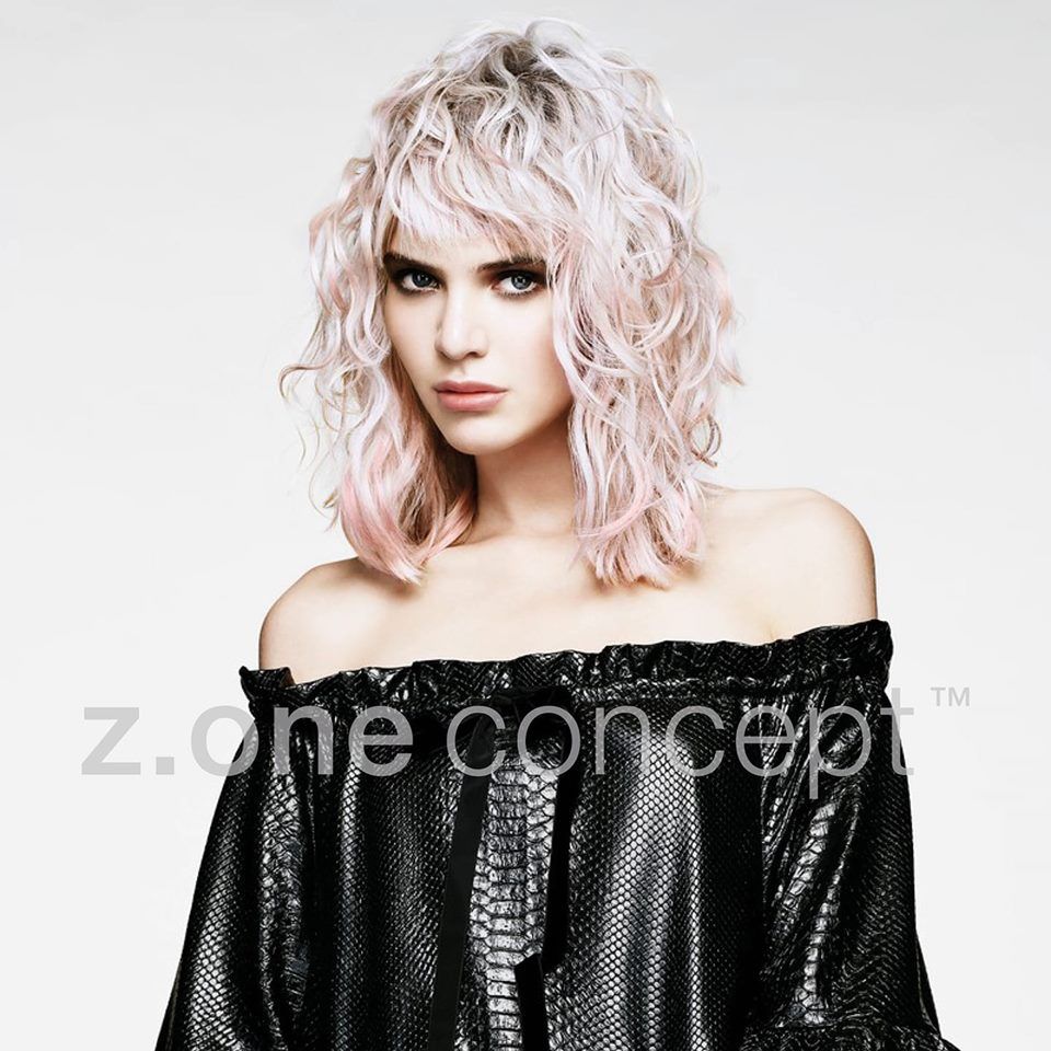 Una mujer con cabello rosa lleva un top negro con hombros descubiertos.