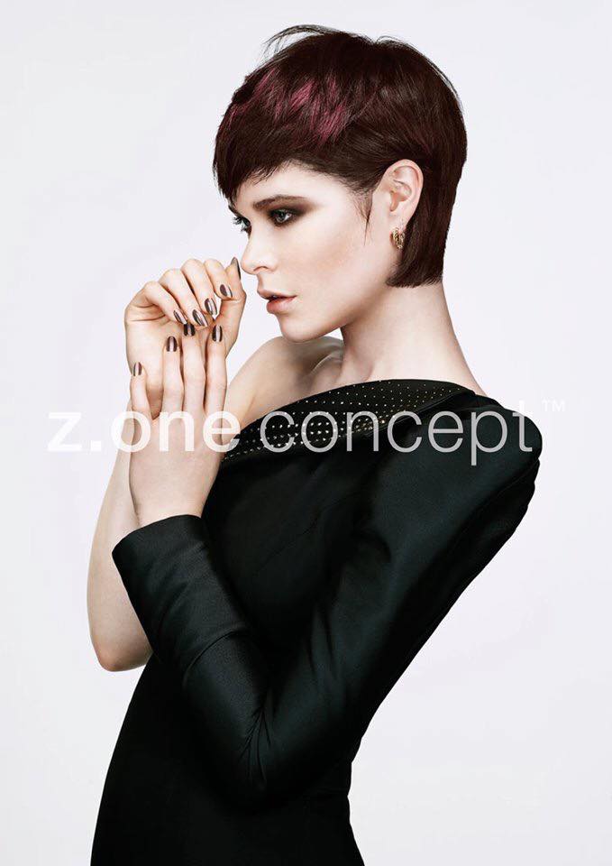 Una mujer con cabello corto y rojo lleva un vestido negro.