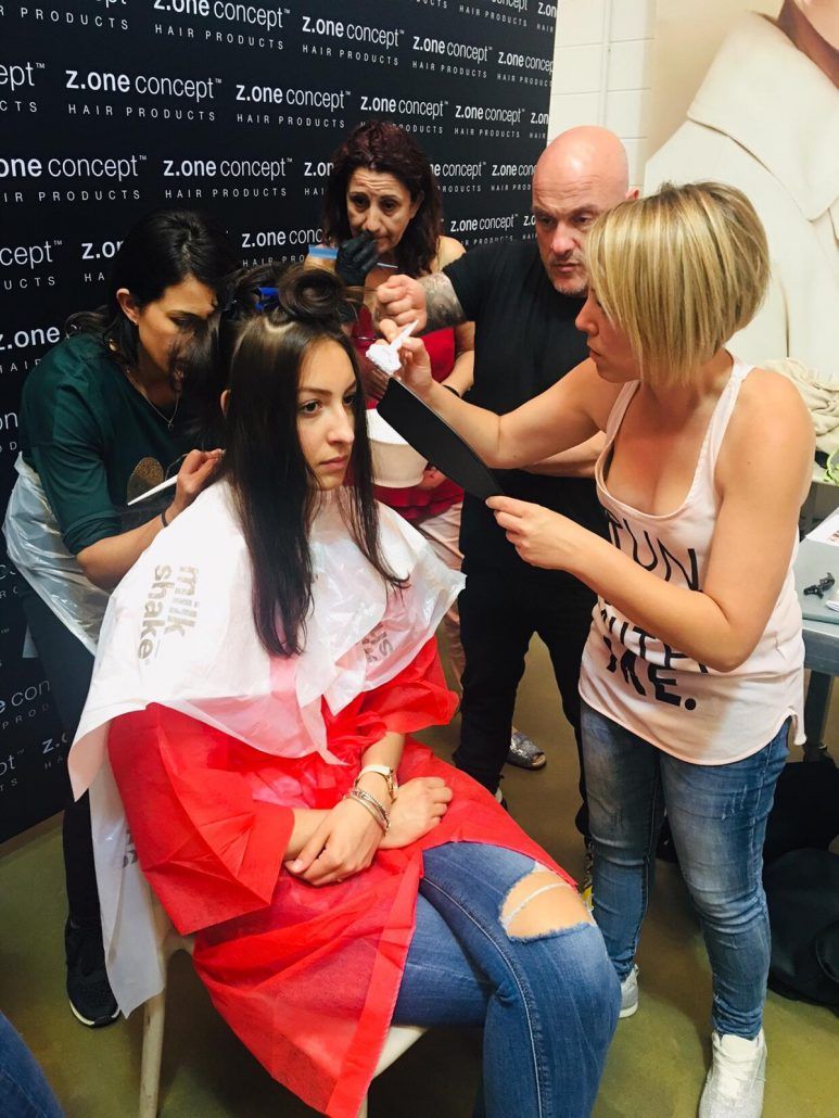 Una mujer se está cortando el pelo por un grupo de personas