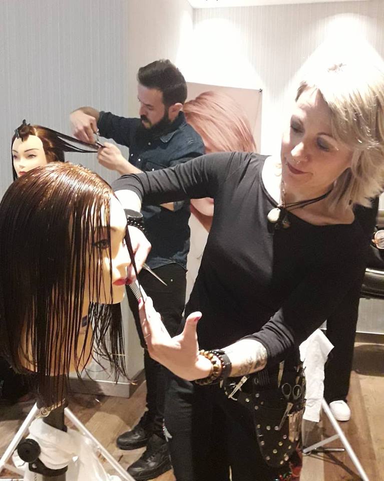 Una mujer está cortando el pelo a un maniquí en un salón.