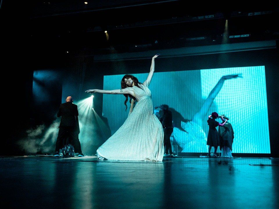 Una mujer con un vestido blanco está bailando en un escenario.