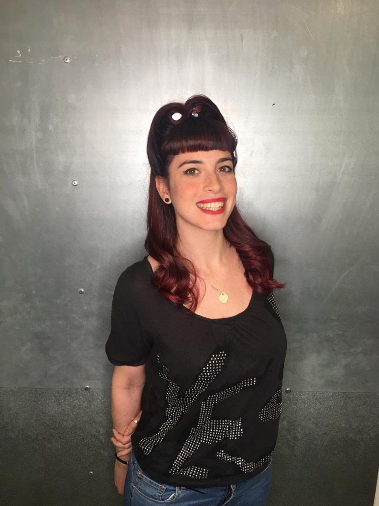 Una mujer pelirroja sonríe y lleva una camisa negra.