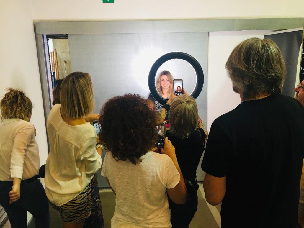 Un grupo de personas está tomando fotografías de una mujer frente a un espejo.