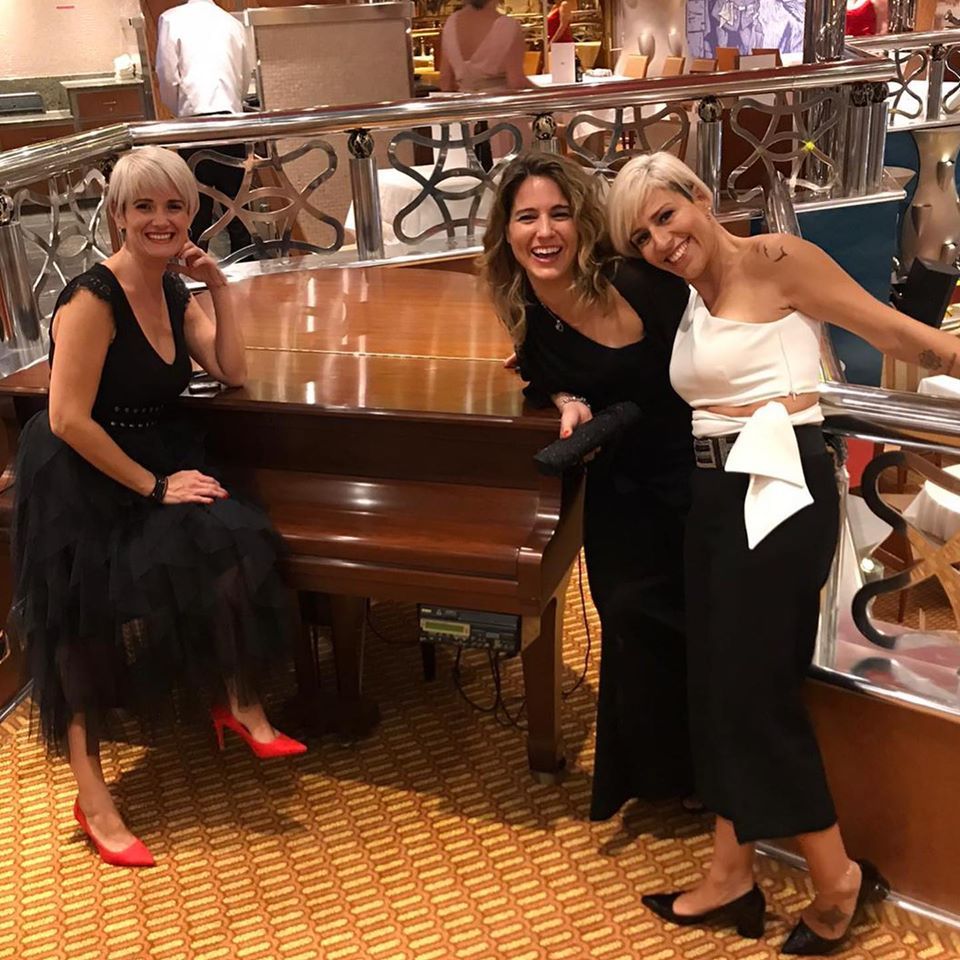 Tres mujeres posan para una foto frente a un piano.
