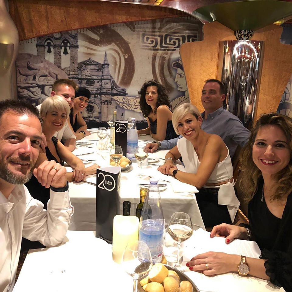 Un grupo de personas está sentado en una mesa larga con un cartel que dice 29.