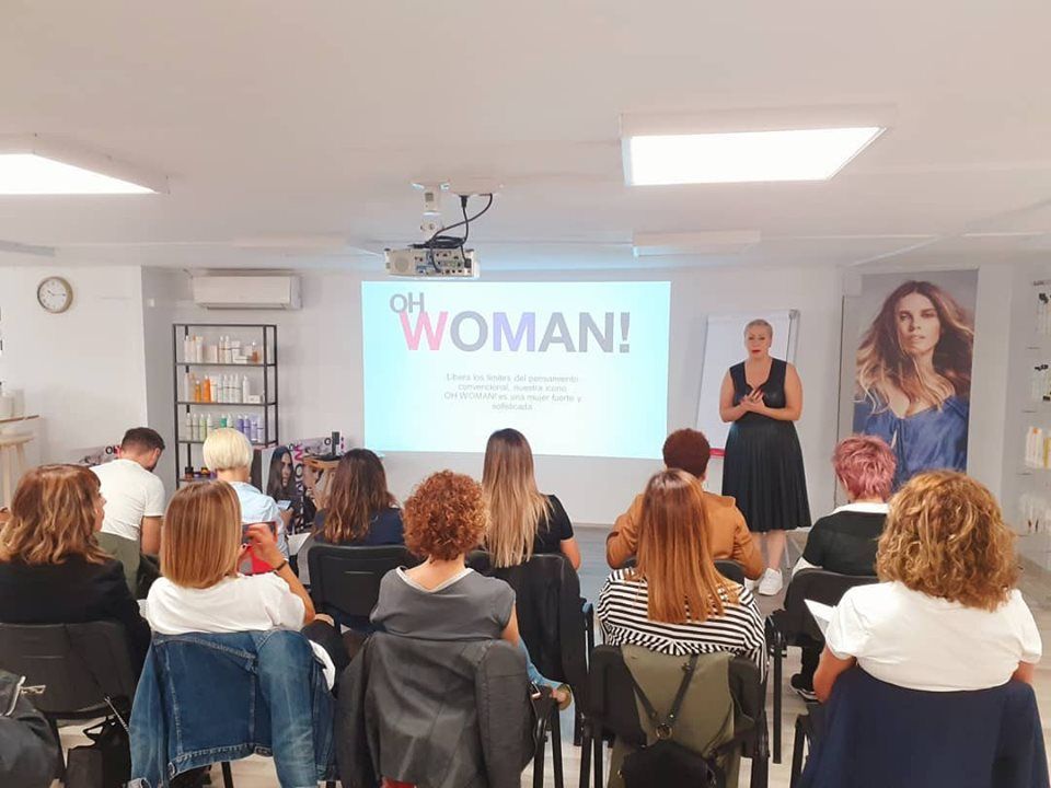 Una mujer está dando una presentación a un grupo de mujeres en una sala.