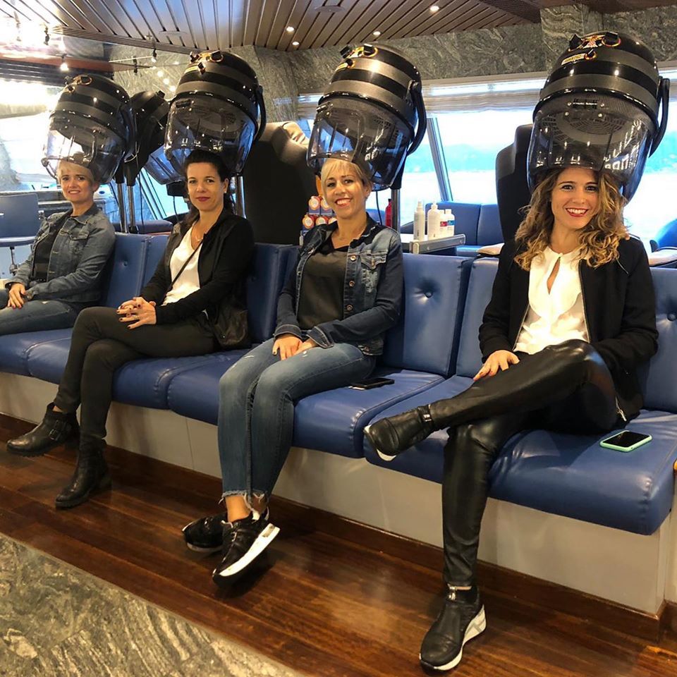 Un grupo de mujeres está sentada en un sofá frente a secadores de pelo.