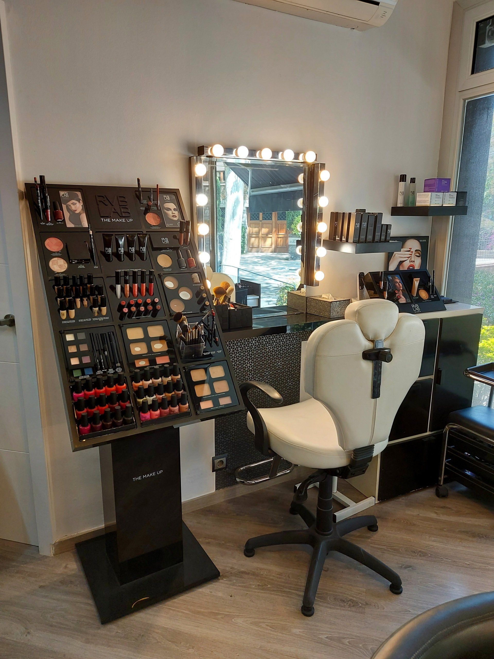 Una habitación con una silla, un espejo y una exposición de maquillaje.