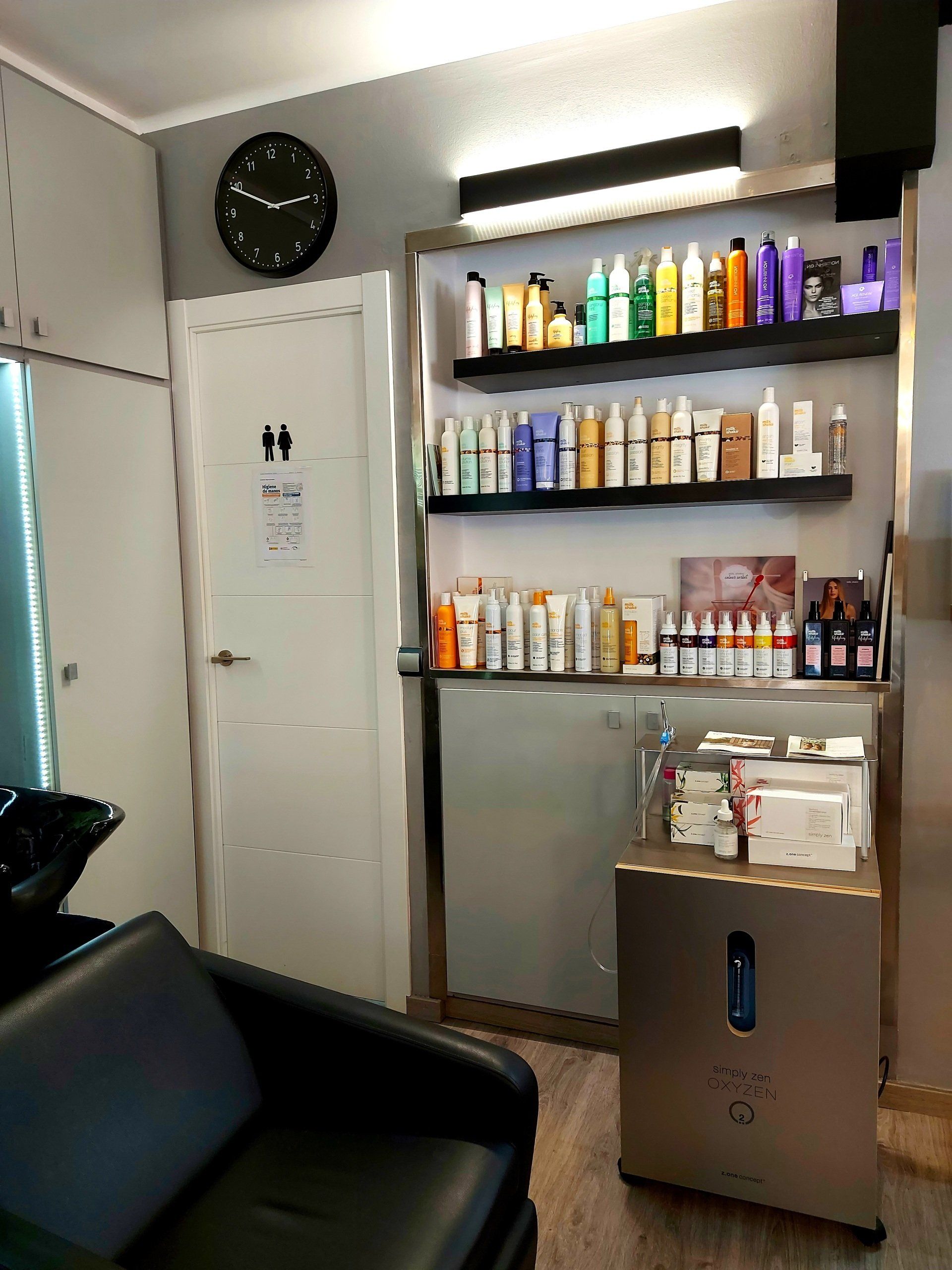 Una peluquería con una silla negra y un reloj en la pared.