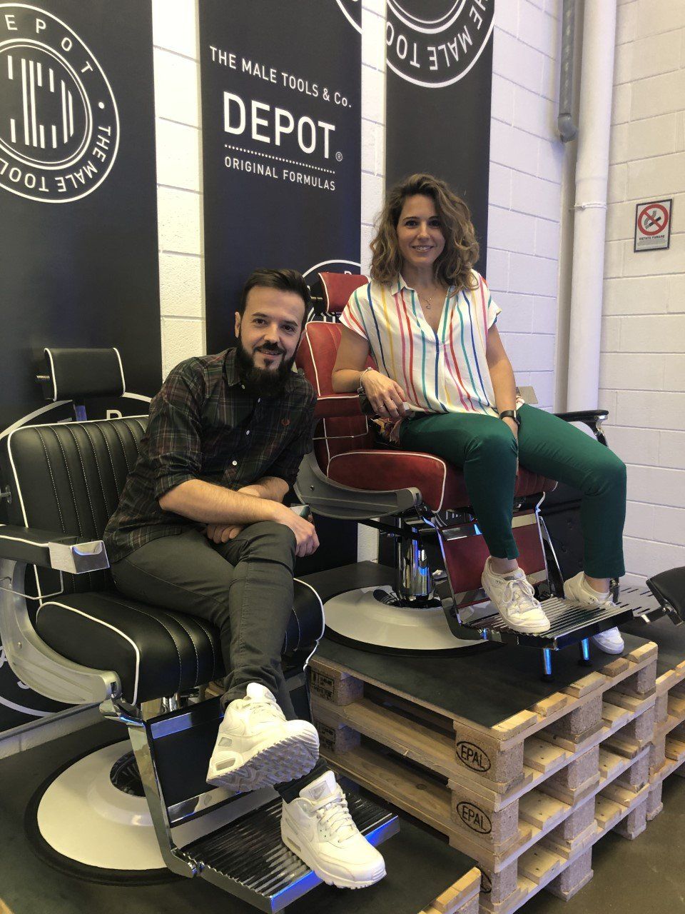 Un hombre y una mujer están sentados en una silla de barbero.