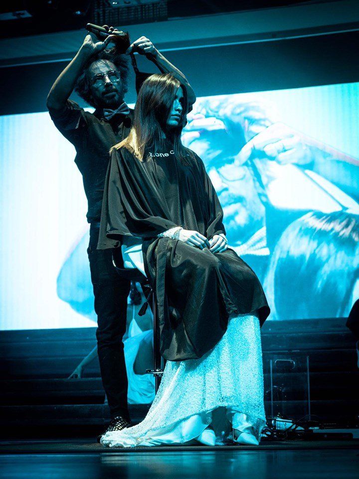 Una mujer está sentada en una silla mientras un hombre le corta el pelo.