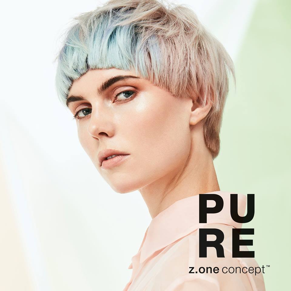 Una mujer con cabello corto azul lleva una camisa rosa.