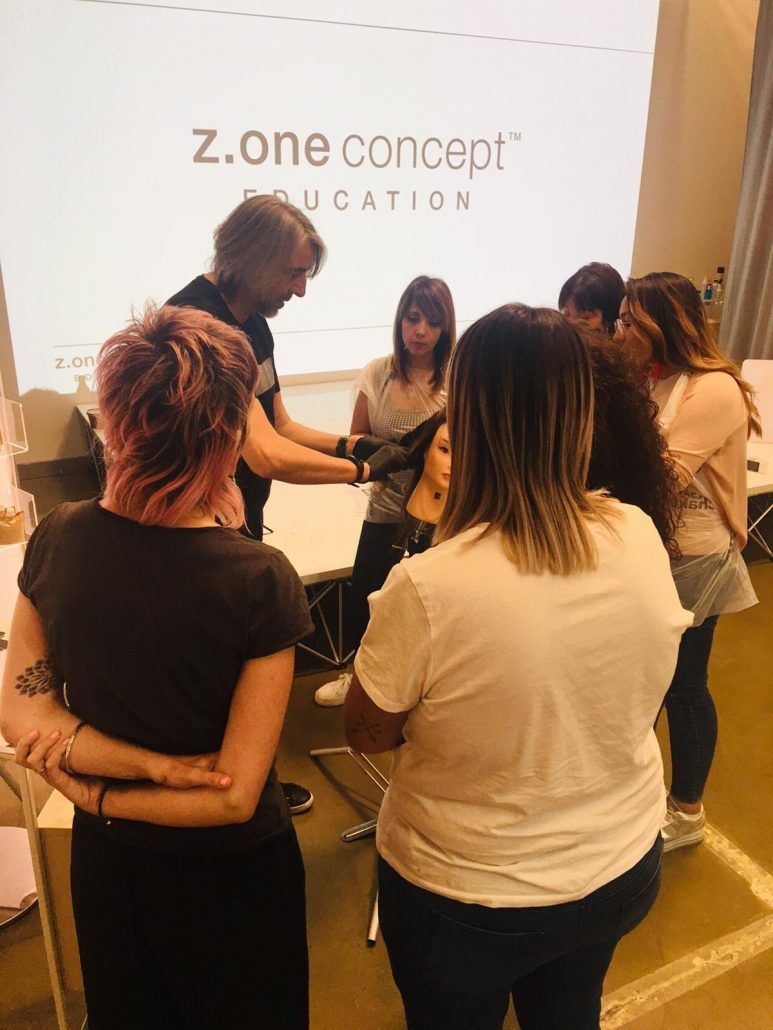 Un grupo de mujeres de pie frente a una pantalla que dice z.one concept