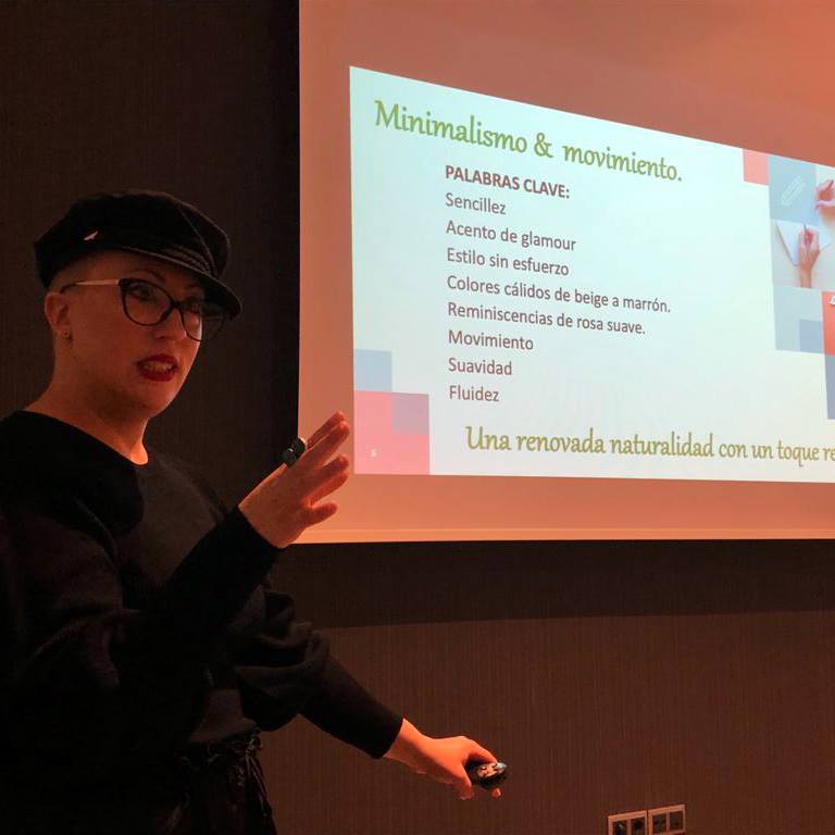 Una mujer está dando una presentación frente a una pantalla que dice minimalismo y movimiento.