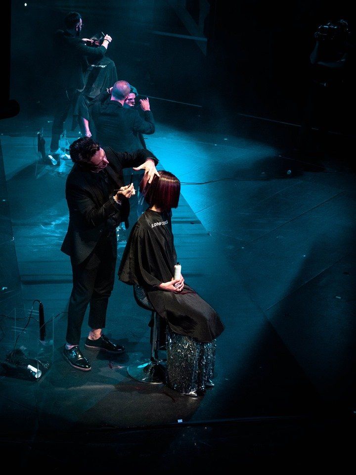 Un hombre está aplicando maquillaje a una mujer en un escenario.