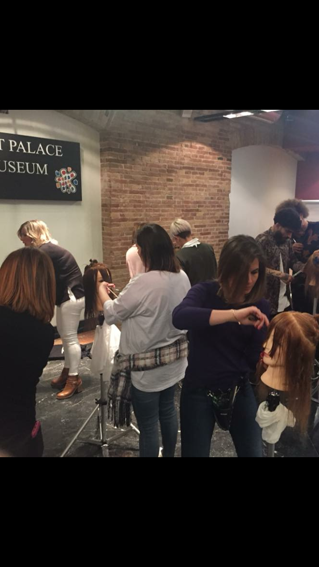 Un grupo de personas están de pie en una habitación cortándose el pelo.