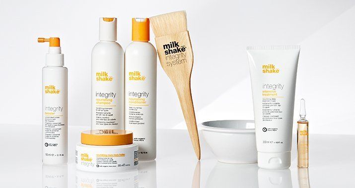 Un grupo de botellas de productos para el cabello en forma de batido de leche están sobre una mesa.