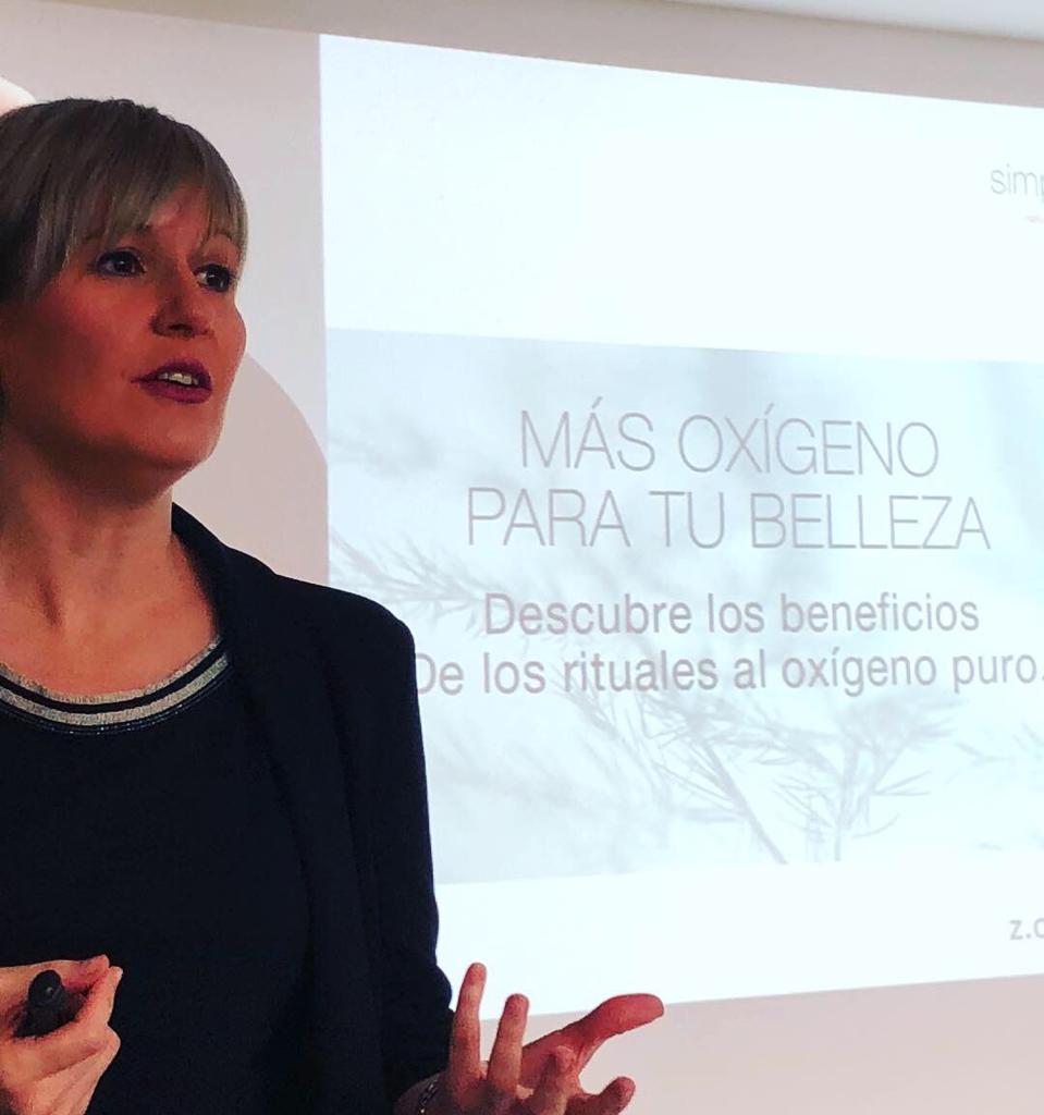 Una mujer está parada frente a una pantalla que dice más oxígeno para tu belleza.