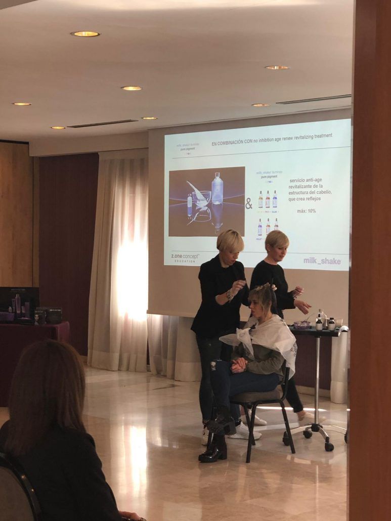 Una mujer se está peinando frente a una pantalla de proyección.