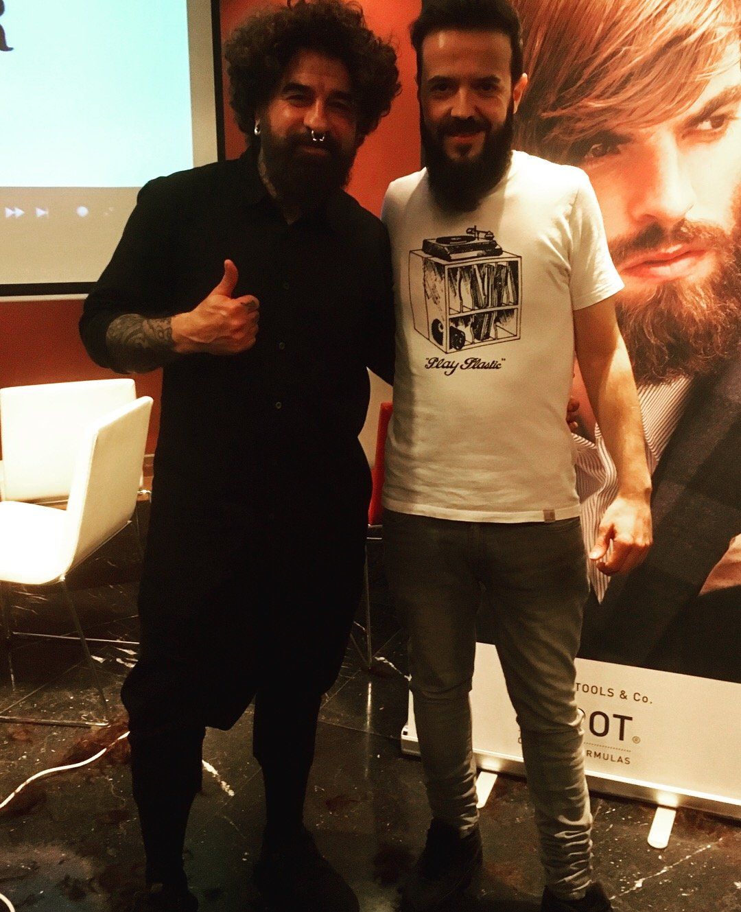 Un hombre con barba está de pie junto a otro hombre.