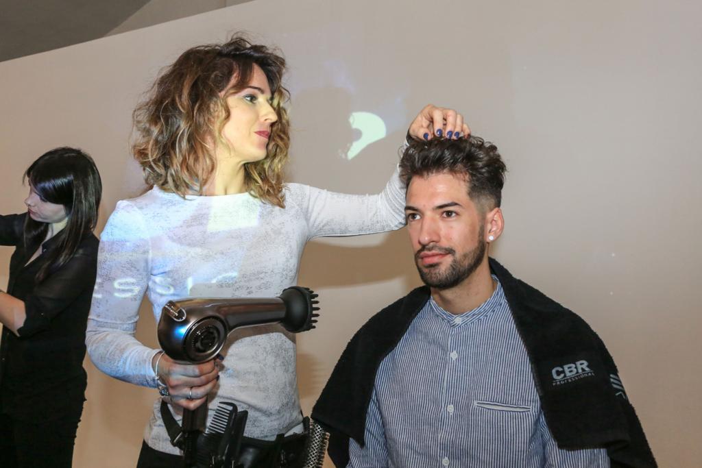 Una mujer está secando el cabello de un hombre en un salón.