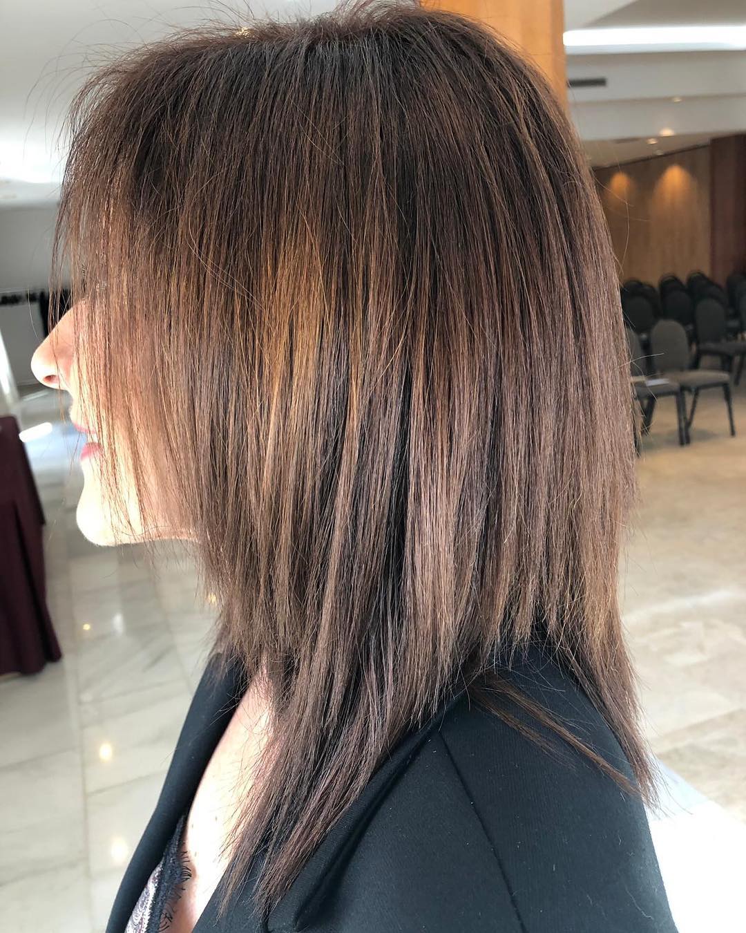 Una mujer con cabello largo y castaño lleva una chaqueta negra.