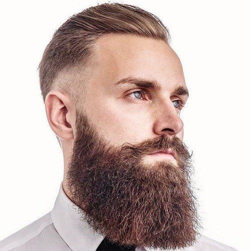 Un hombre con barba y bigote lleva una camisa blanca y corbata.