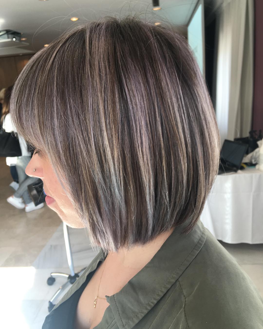 Una mujer con pelo corto lleva una camisa verde.