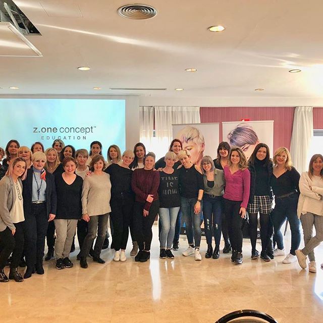 Un grupo de personas posa para una foto frente a una pantalla que dice z.one concept