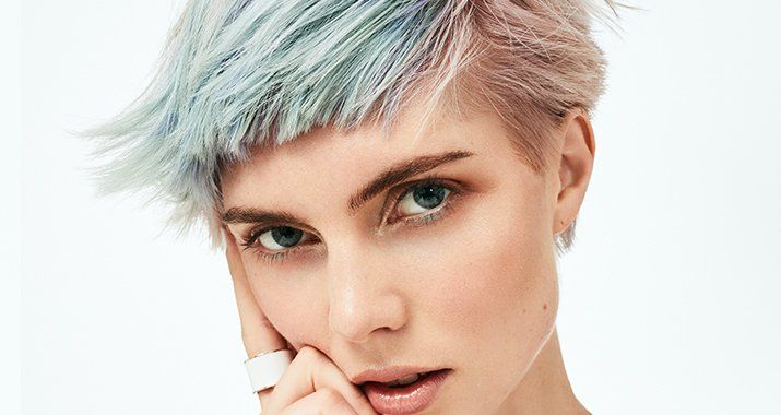 Un primer plano del rostro de una mujer con cabello corto y un anillo en el dedo.