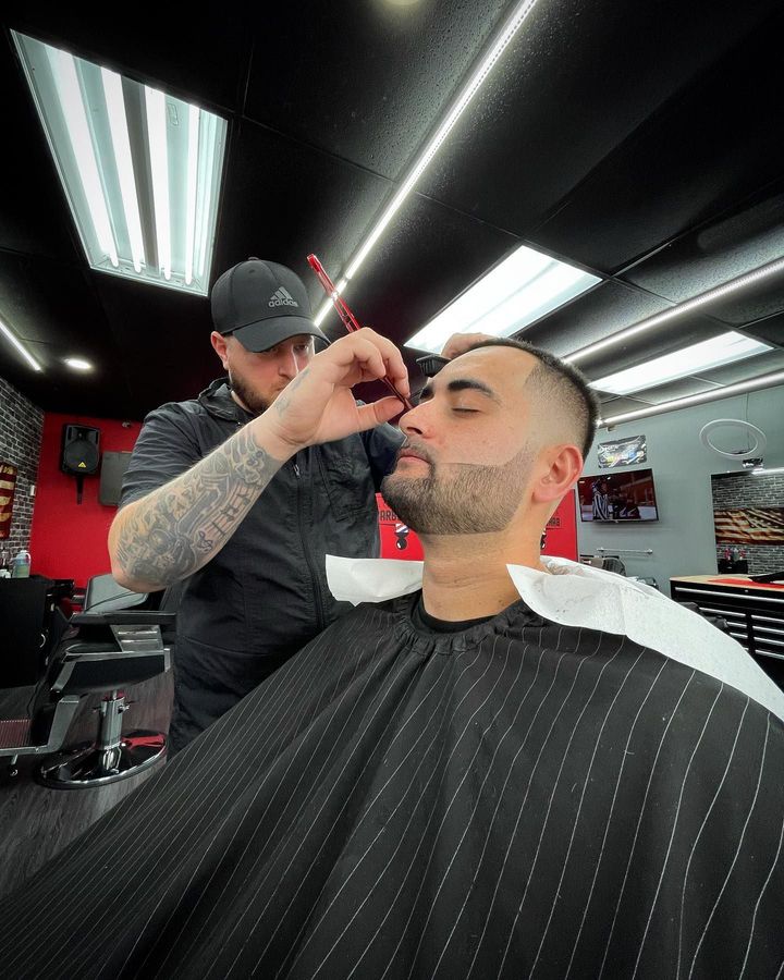 A man is getting his beard shaved by a barber.