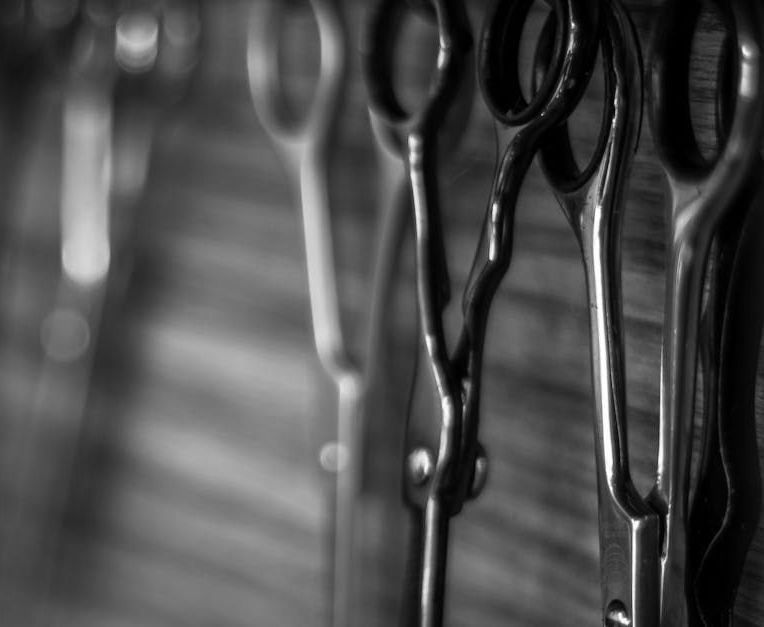 A black and white photo of a row of scissors hanging on a wall.