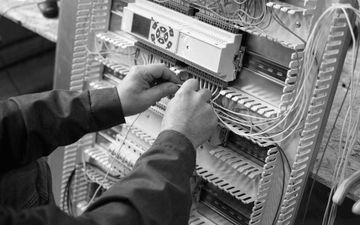 Technician wiring a switch in an electrical control panel with neatly organized cables