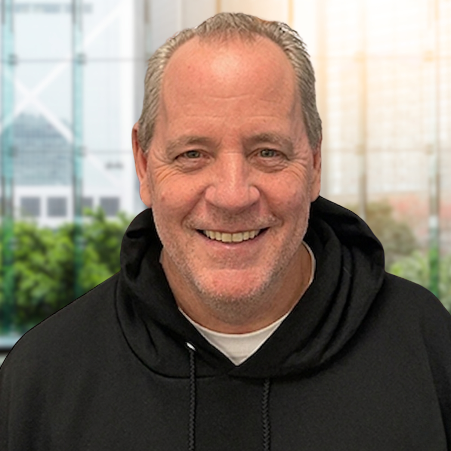 Smiling man in a black hoodie indoors with a blurred office background