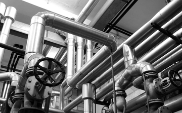 Industrial pipes and valves overhead in a metallic plant interior