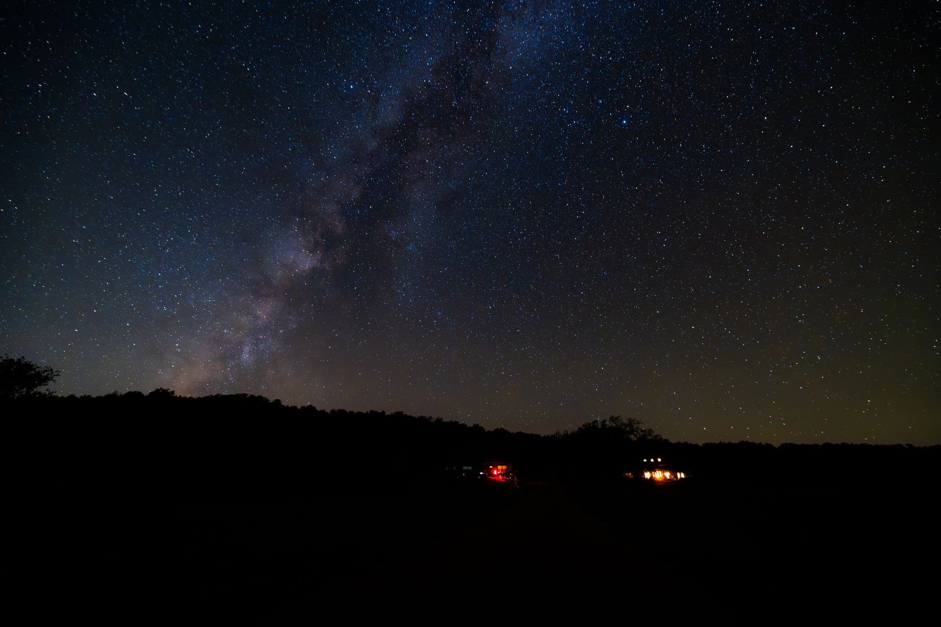 A night sky filled with lots of stars and a house in the foreground.