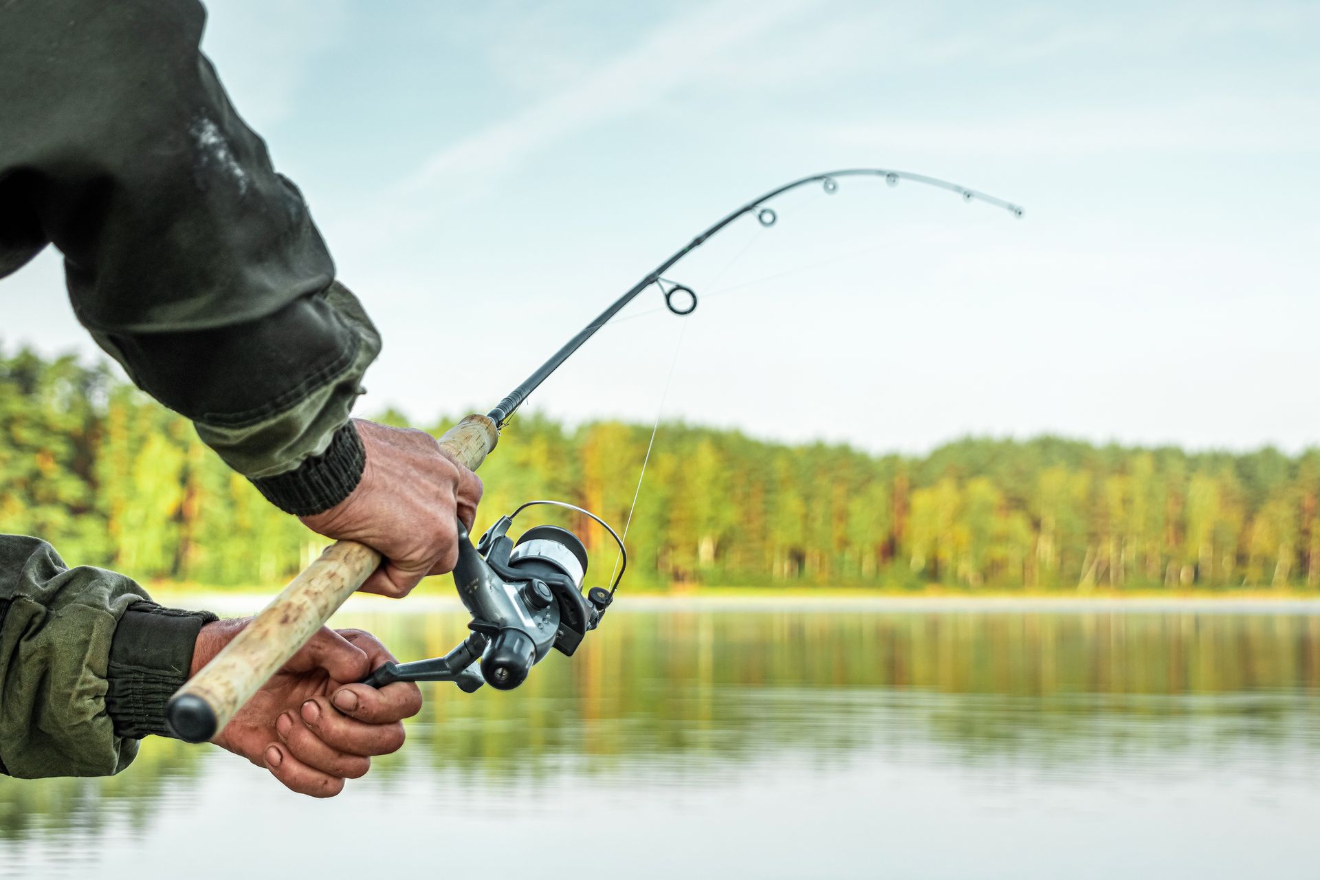 A man is fishing on a lake with a fishing rod and reel.