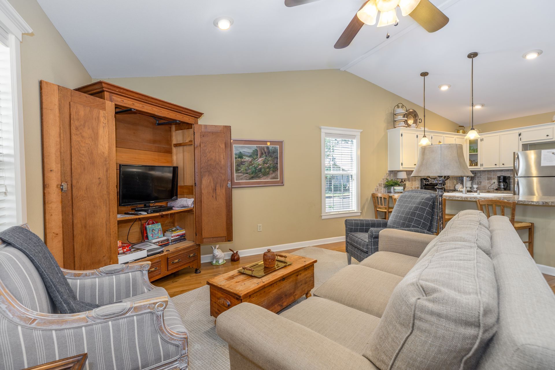 A living room with a couch , chairs , a television and a ceiling fan.