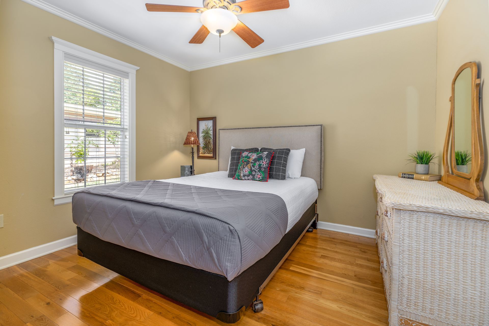 A bedroom with a bed , dresser , mirror and ceiling fan.