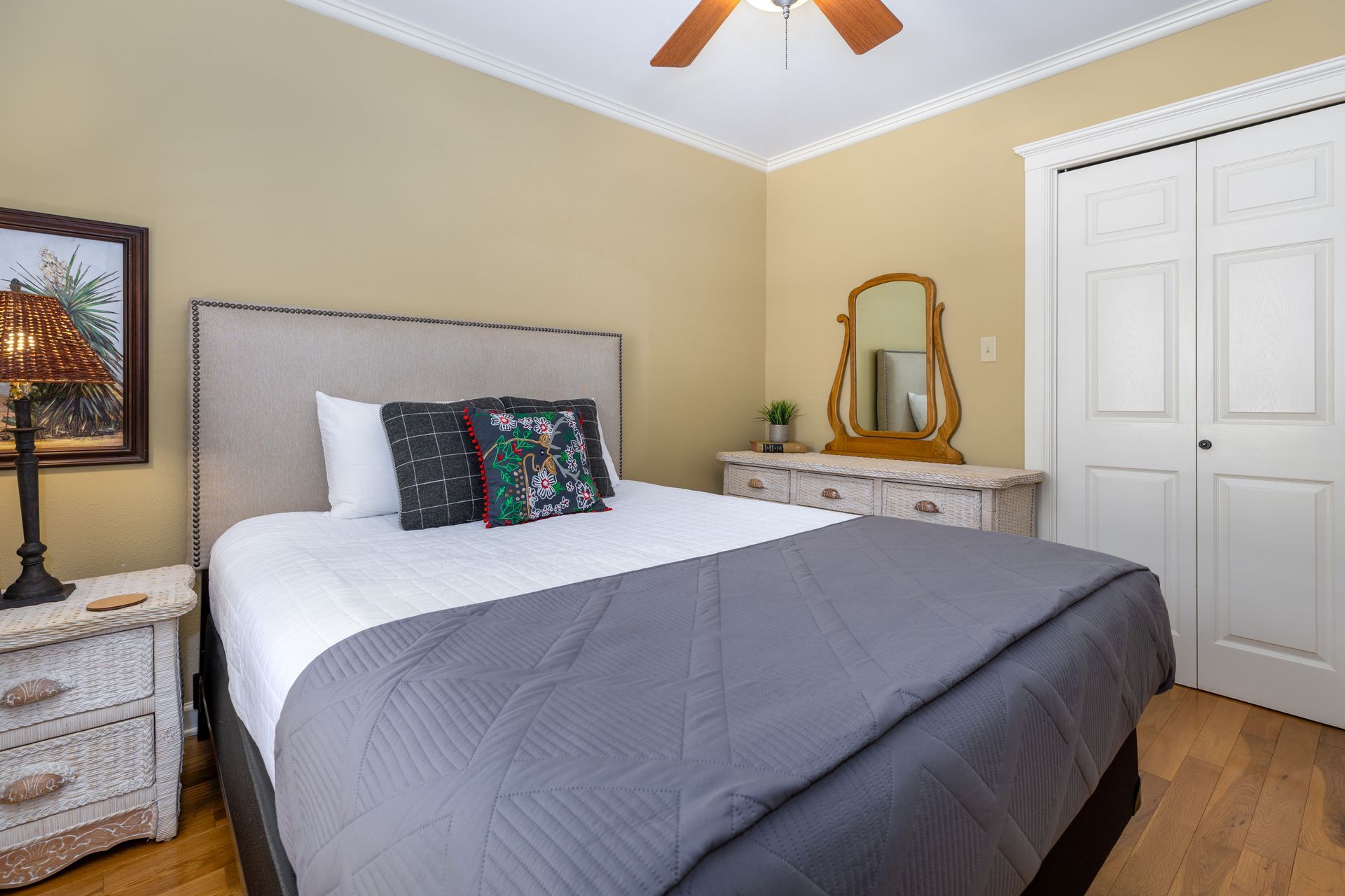 A bedroom with a bed , nightstand , mirror and ceiling fan.