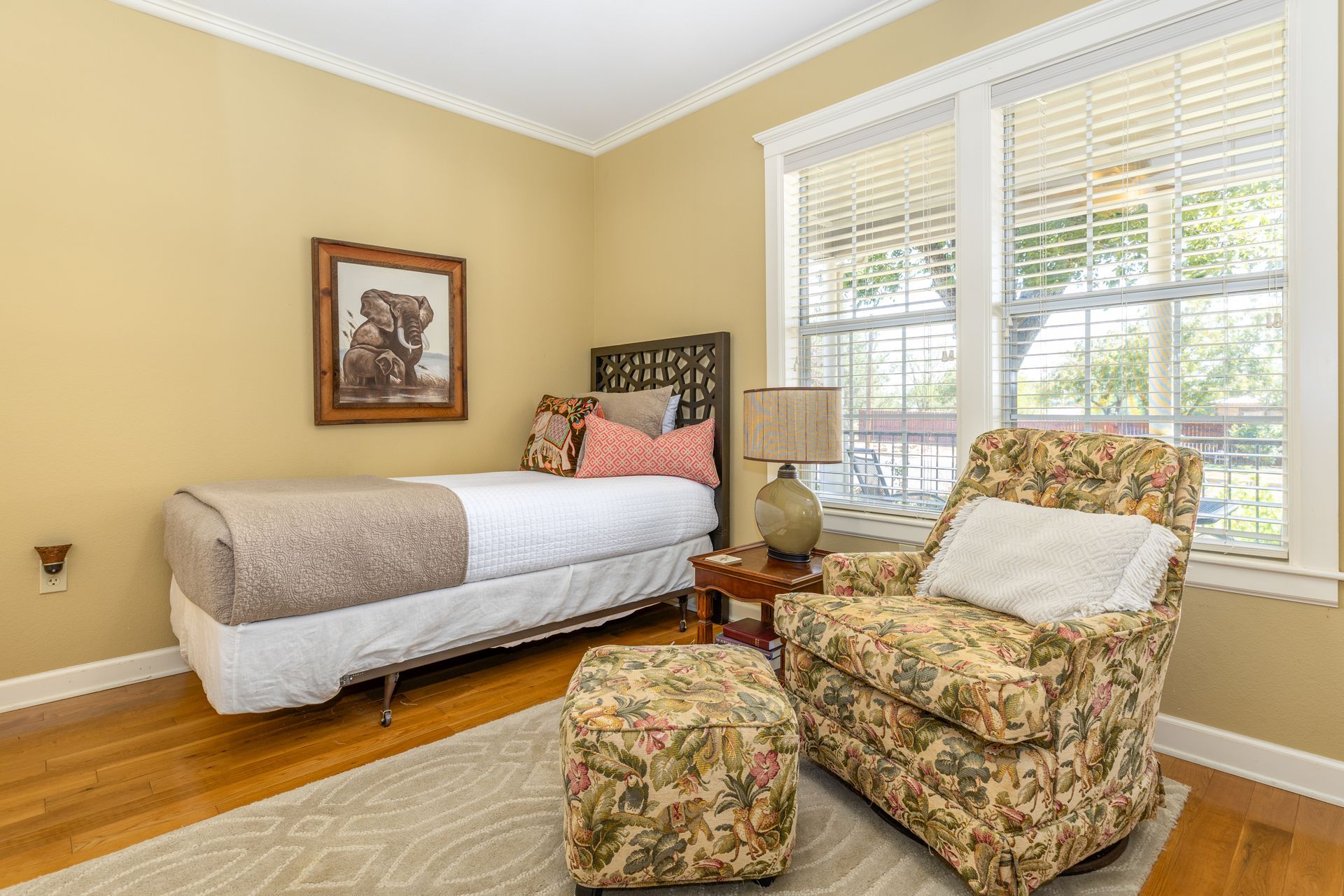 A bedroom with a bed , chair and ottoman.