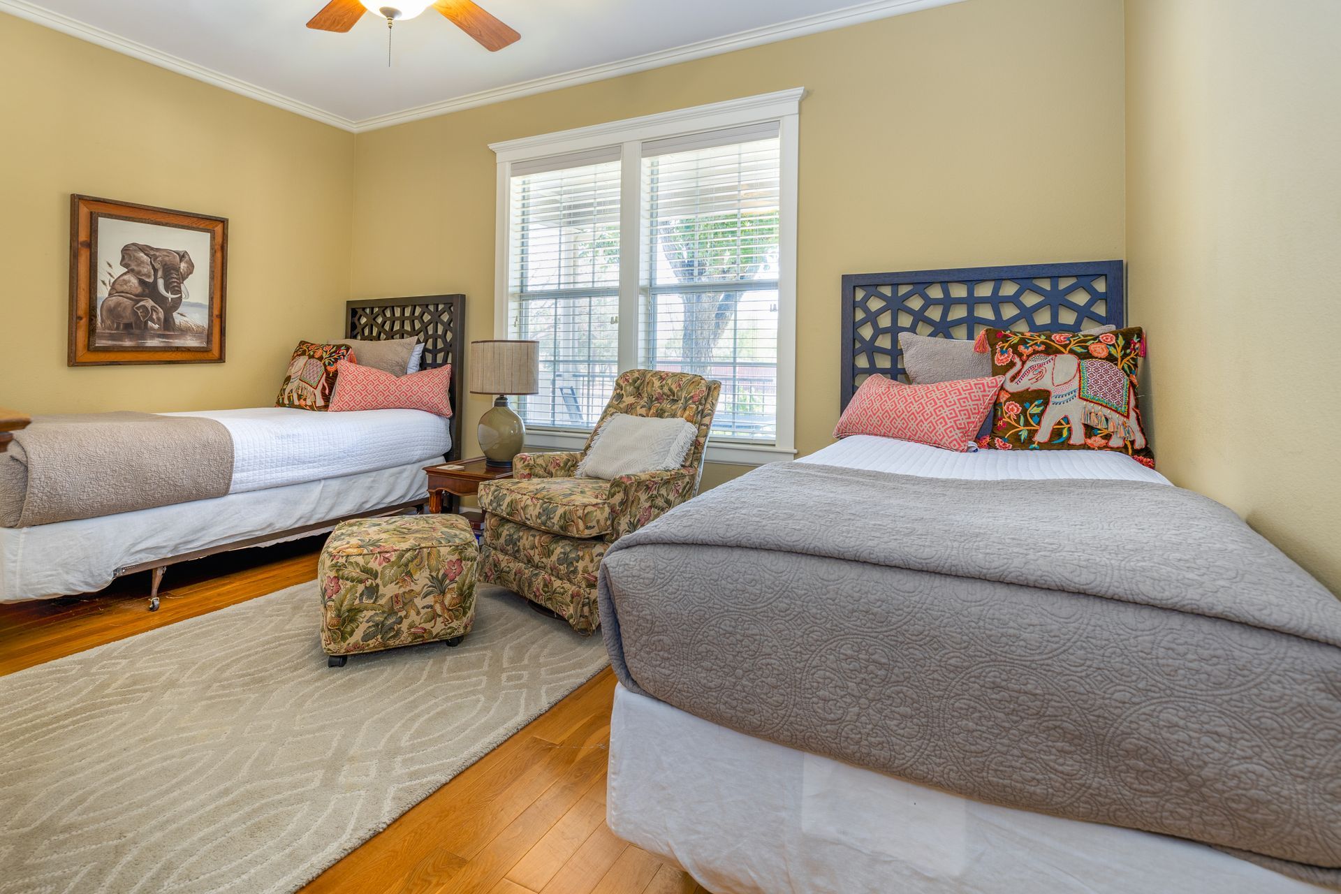 A bedroom with two beds , two chairs and a ceiling fan.